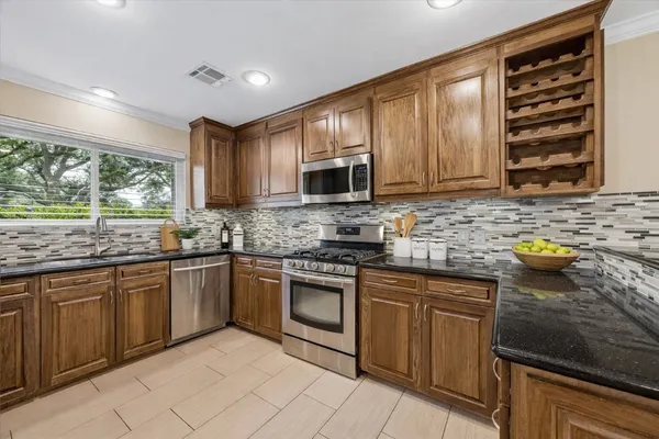 a kitchen with granite countertop a sink stainless steel appliances and cabinets