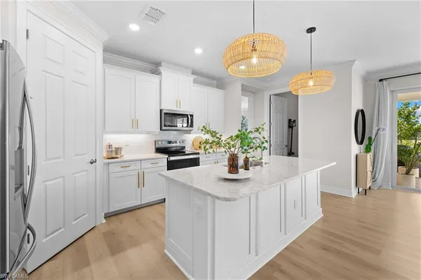 a kitchen with stainless steel appliances granite countertop a sink a stove a refrigerator a microwave oven with white cabinets