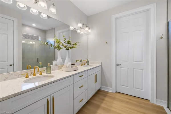 a spacious bathroom with double vanity a mirror and a shower