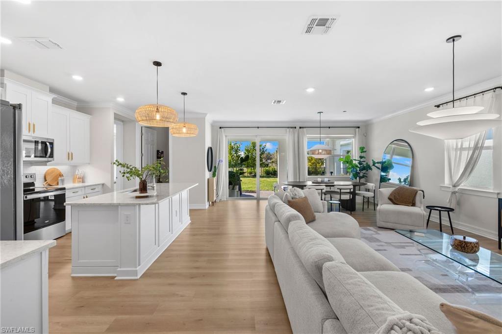 488 Polihale Way Naples, FL 34114 - Photo 6 of 49 a large living room with stainless steel appliances kitchen island granite countertop lots of white furniture a chandelier a large window and a chandelier