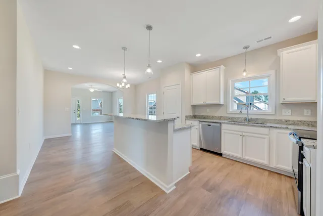a large kitchen with granite countertop a large counter top a sink stainless steel appliances and cabinets