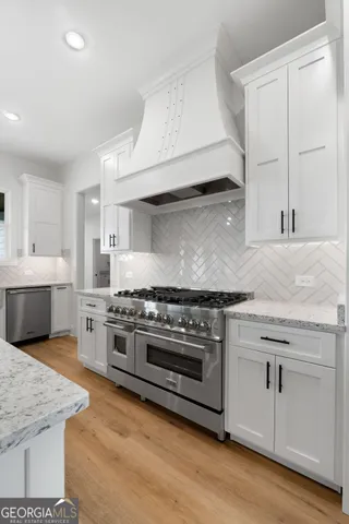 a kitchen with stainless steel appliances a stove and white cabinets