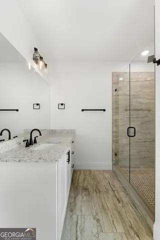 a bathroom with a granite countertop sink a mirror and shower