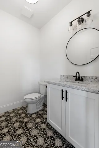 a bathroom with a granite countertop toilet sink and mirror