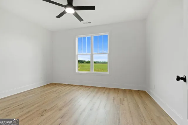 an empty room with a window and a ceiling fan