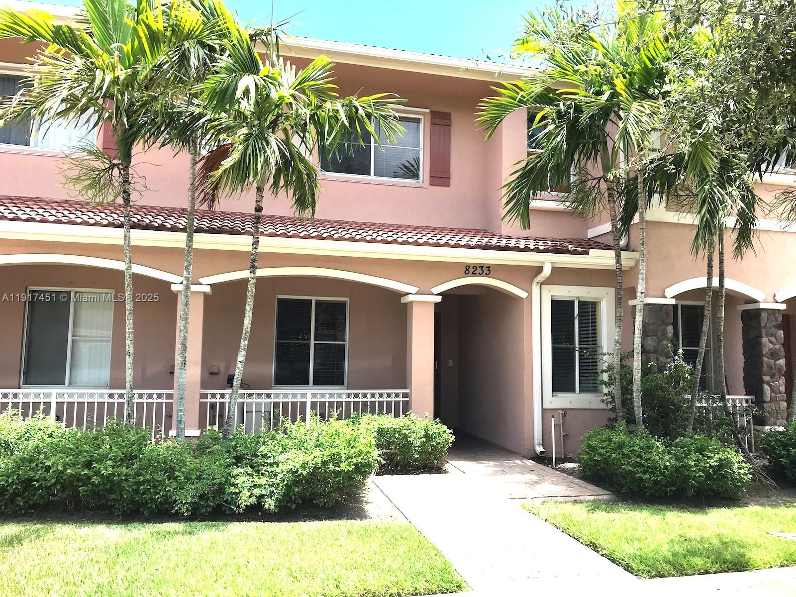 8233 Southwest 25th Court, Unit 104 Miramar, FL 33025 - Photo 22 of 22 a view of a white house with a large windows and a yard with plants and palm trees