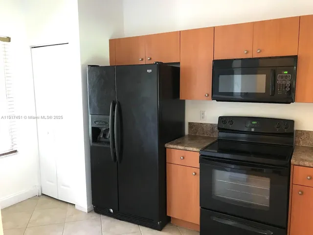a kitchen with granite countertop a refrigerator and a sink