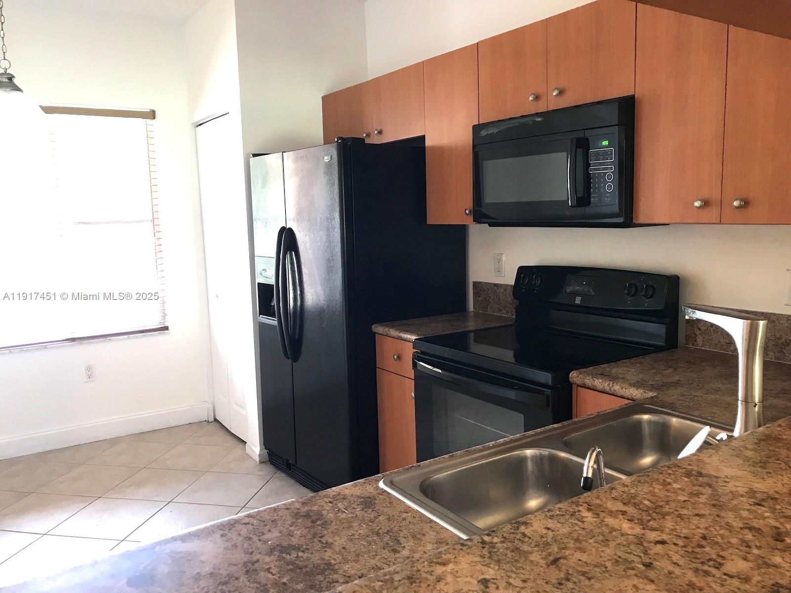 8233 Southwest 25th Court, Unit 104 Miramar, FL 33025 - Photo 6 of 22 a kitchen with granite countertop a refrigerator and a sink