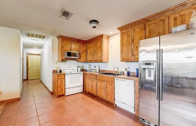 a kitchen with stainless steel appliances granite countertop a refrigerator a stove and a sink