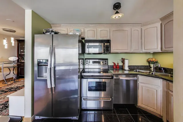 a kitchen with stainless steel appliances granite countertop a refrigerator sink and stove