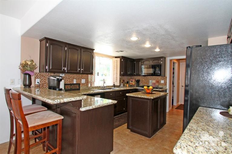 68565 Senora Road Cathedral City, CA 92234 - Photo 13 of 37 a kitchen with stainless steel appliances granite countertop a stove top oven a sink dishwasher a dining table and chairs with wooden floor