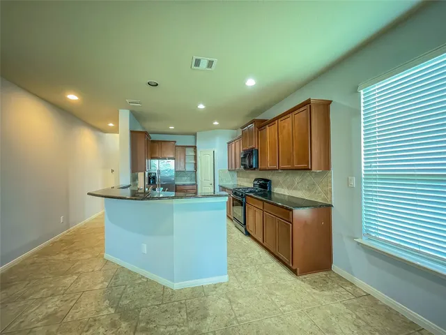 a kitchen with stainless steel appliances granite countertop sink stove top oven and cabinets