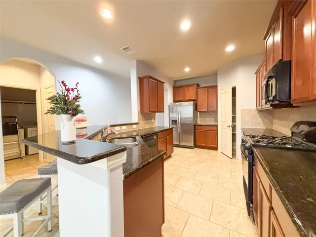 a kitchen with stainless steel appliances granite countertop a sink stove and refrigerator