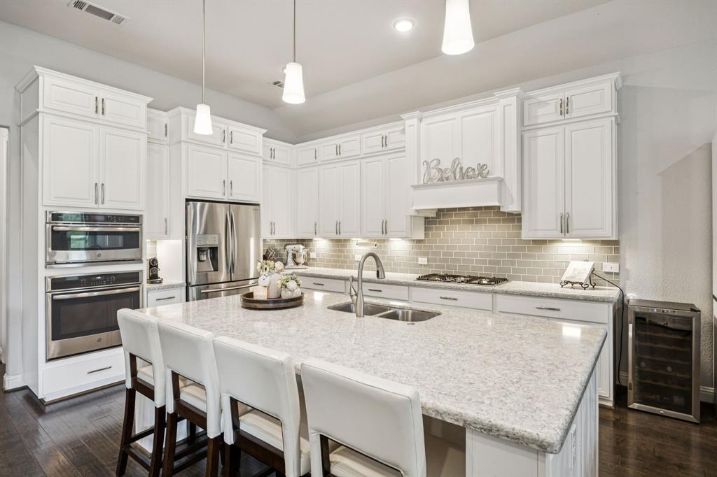 8116 Tramore The Colony, TX 75056 - Photo 9 of 36 a kitchen with kitchen island granite countertop a table chairs stove and cabinets