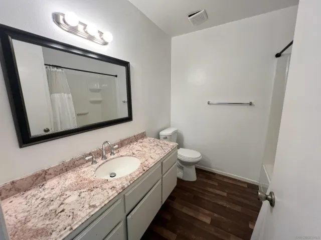 a bathroom with a granite countertop sink mirror vanity and toilet