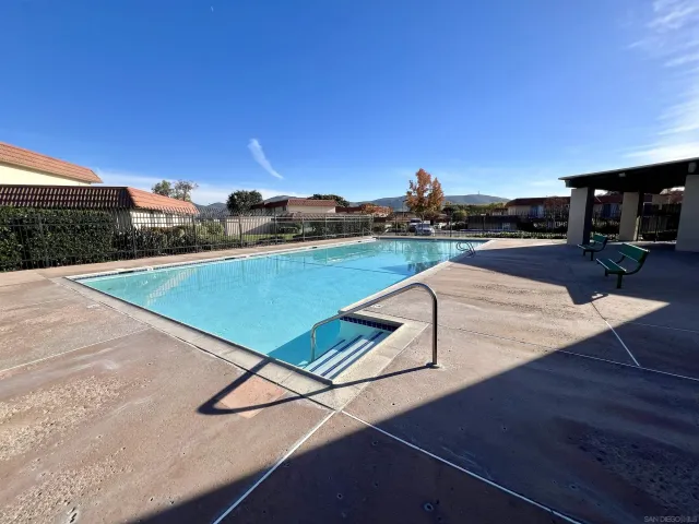 a view of swimming pool with seating area and trees in the background