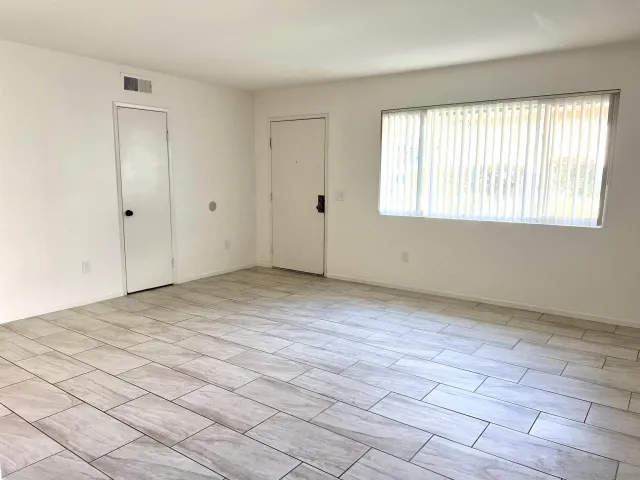 a view of an empty room with window and hardwood floor