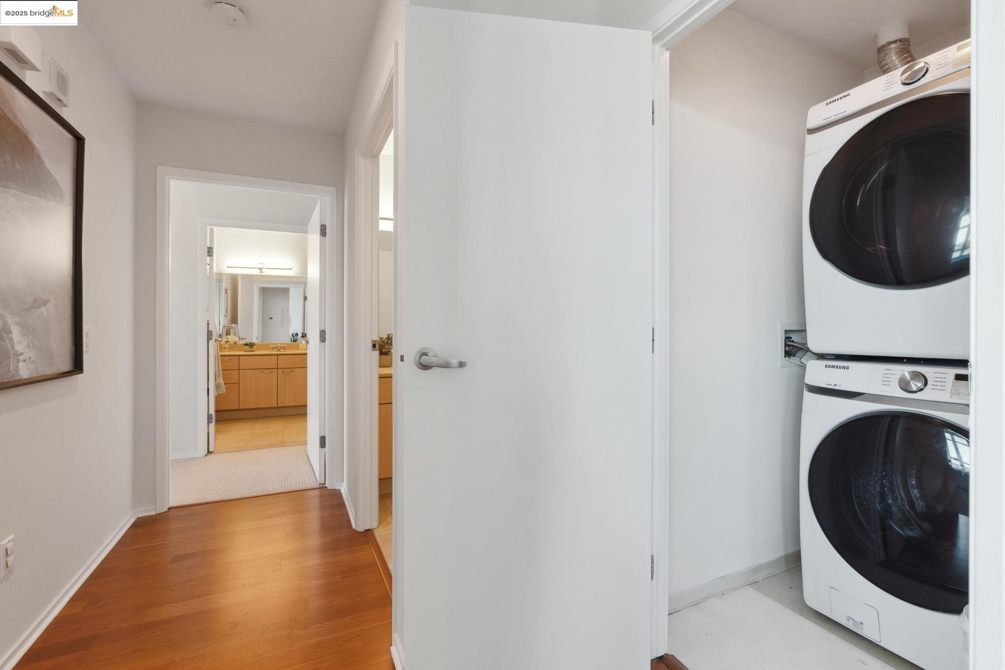 1 Lakeside Drive, Unit 1010 Oakland, CA 94612 - Photo 27 of 47 Laundry room featuring light wood-style flooring and estacked washer and dryer