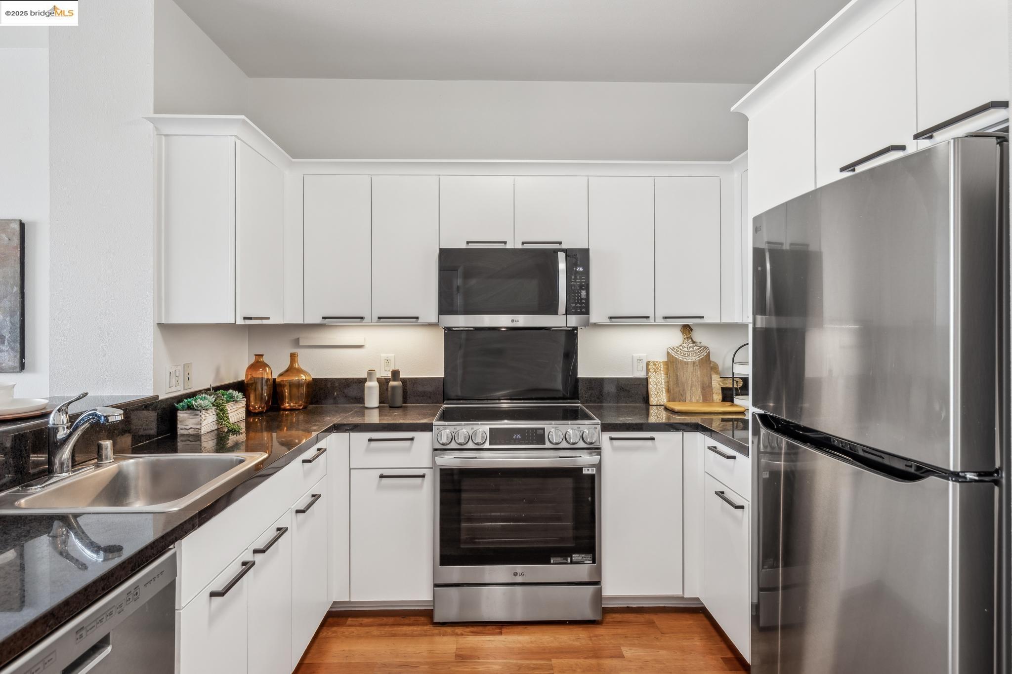 1 Lakeside Drive, Unit 1010 Oakland, CA 94612 - Photo 10 of 47 Kitchen with appliances with stainless steel finishes, white cabinets, and light wood finished floors