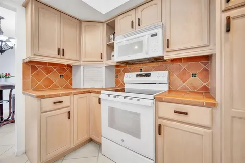 a view of a kitchen with white cabinets and washer dryer