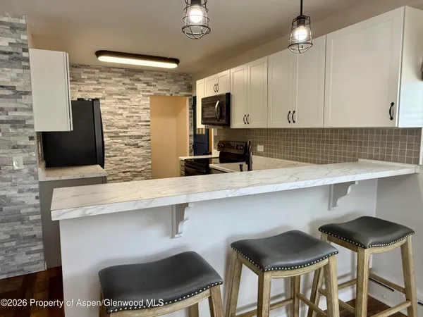 a kitchen with a sink dishwasher a refrigerator a stove and white cabinets with wooden floor