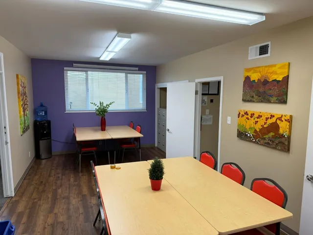 a kitchen with stainless steel appliances wooden floor dining table and chairs in it