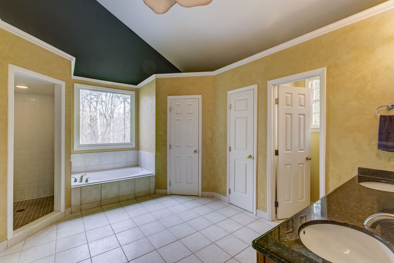12312 Galway Drive Raleigh, NC 27613 - Photo 15 of 25 The master luxury 2-story spa bath features a double granite vanity with triple globe fixtures, His & Her closets, decorative stucco finish on walls, tile floors, jetted garden tub, walk-in tile surround shower, separate water closet, and ceiling fan. Master Bath