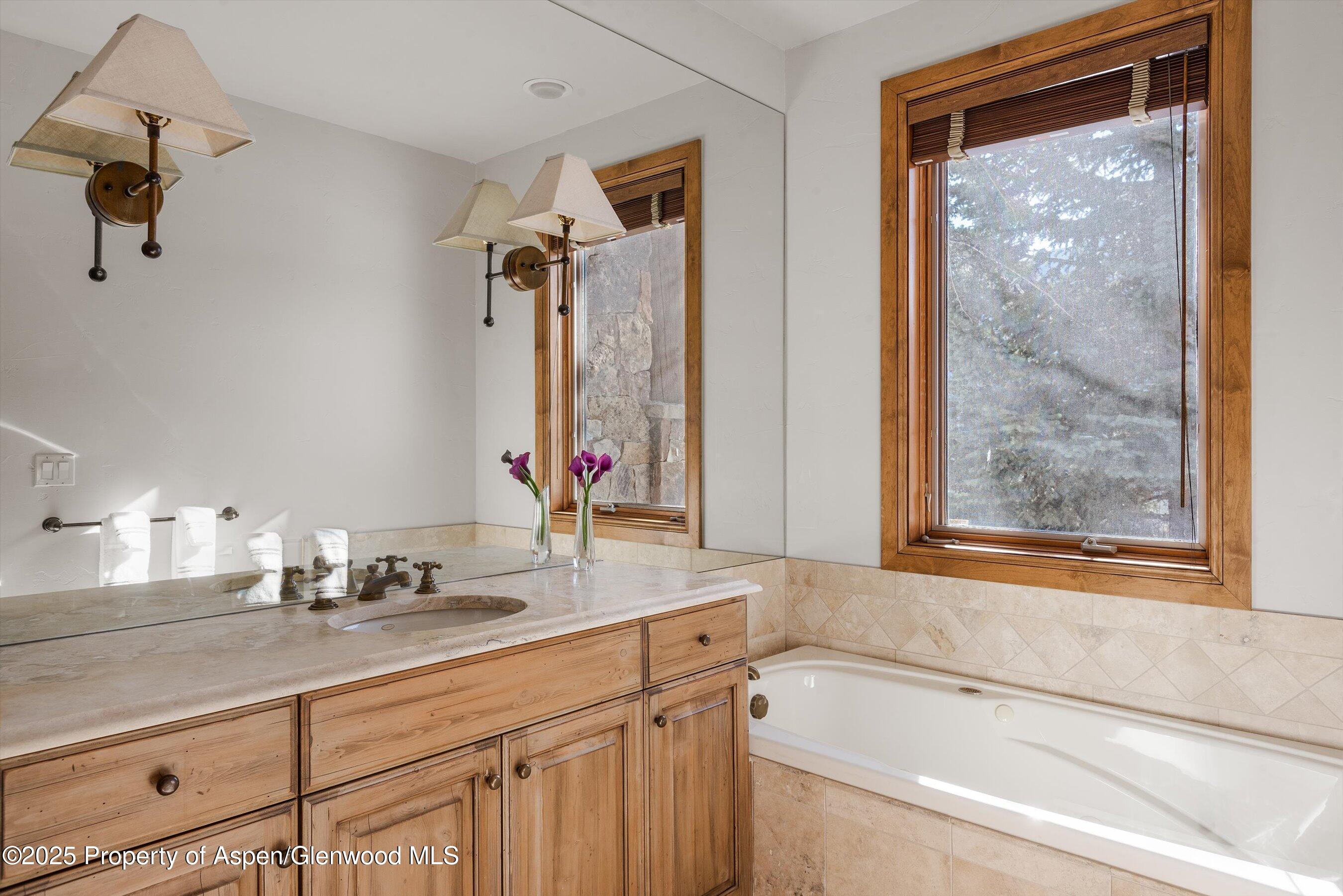 415 Silverlode Drive Aspen, CO 81611 - Photo 18 of 26 a bathroom with a granite countertop tub sink and mirror