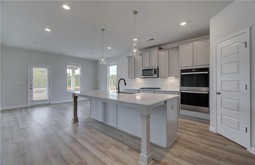 100 Felicity Pike Locust Grove, GA 30248 - Photo 14 of 38 a large kitchen with kitchen island a sink dishwasher a stove and a refrigerator with wooden floor