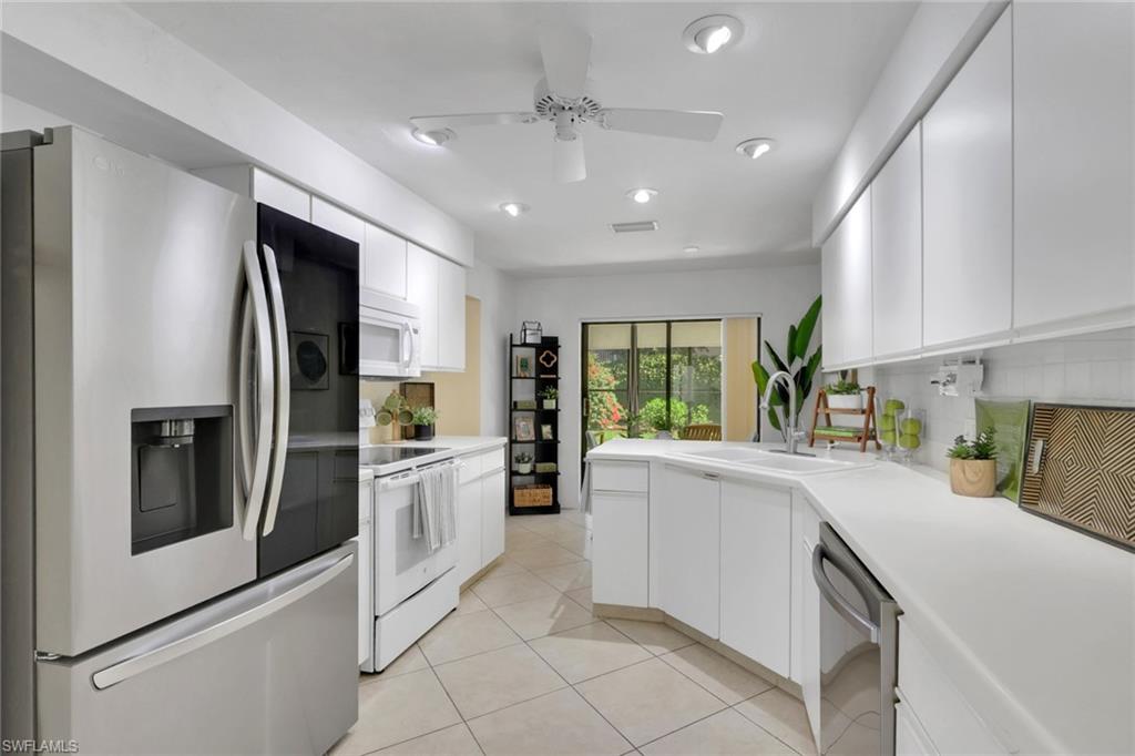796 Reef Point Circle Naples, FL 34108 - Photo 16 of 37 a kitchen with white cabinets and stainless steel appliances