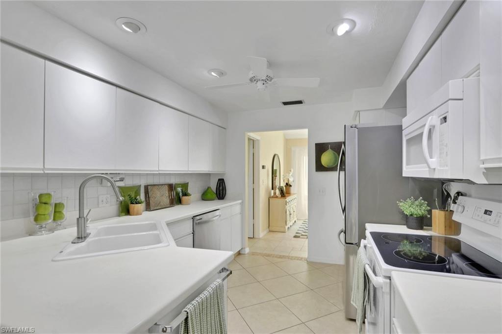 796 Reef Point Circle Naples, FL 34108 - Photo 17 of 37 a kitchen with stainless steel appliances kitchen island granite countertop a refrigerator a sink a stove and white cabinets