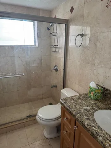 a bathroom with a granite countertop sink a toilet and shower