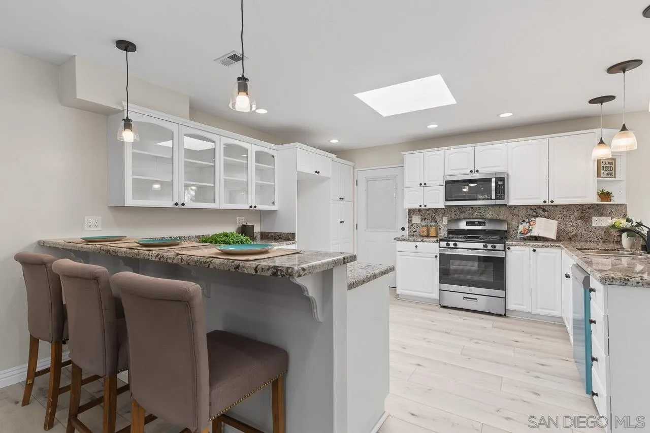 2922 Olive View Road Alpine, CA 91901 - Photo 5 of 34 a kitchen with stainless steel appliances granite countertop a stove a sink a oven a refrigerator and white cabinets with wooden floor