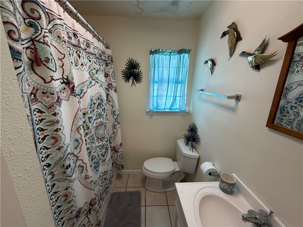 104 Jonathan Street Three Rivers, TX 78071 - Photo 13 of 17 a bathroom with a toilet and a shower curtain