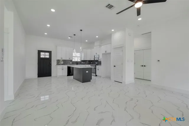 a large white kitchen with stainless steel appliances granite countertop a sink and cabinets