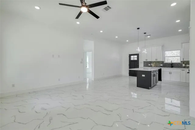 an empty room with chandelier fan and windows