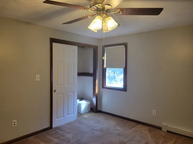 an empty room with windows and chandelier fan