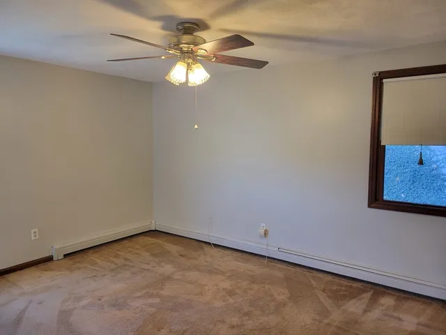 an empty room with a window and a fan