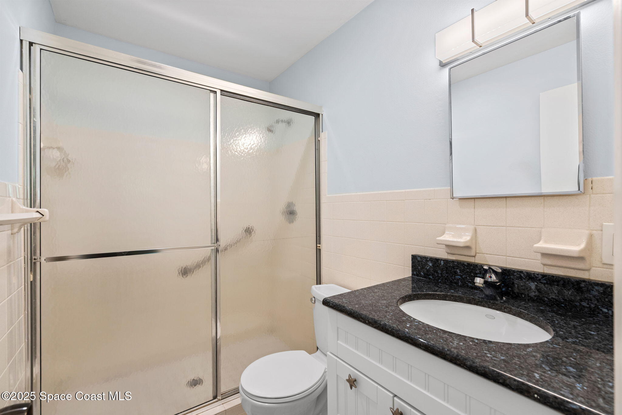 2902 Emory Street Melbourne, FL 32901 - Photo 40 of 46 a bathroom with a granite countertop sink toilet mirror and a shower