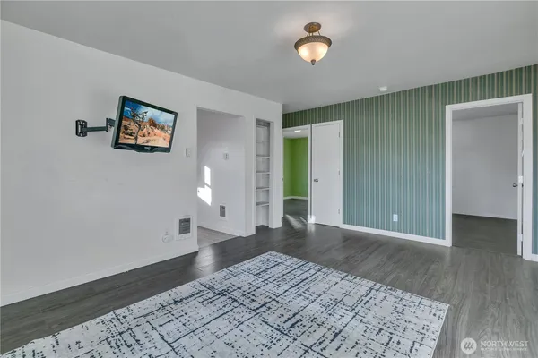 a view of a big room with wooden floor and windows