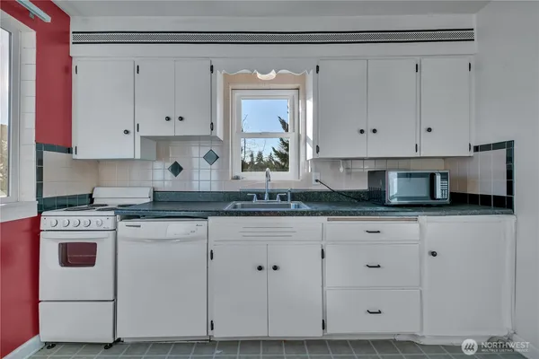 a kitchen with granite countertop white cabinets and white appliances