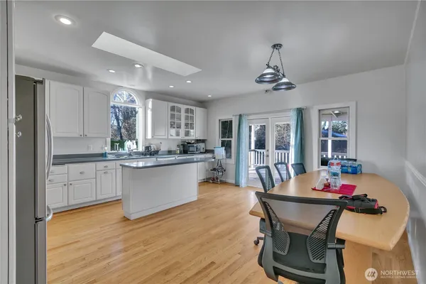a kitchen with stainless steel appliances kitchen island granite countertop a dining table chairs and sink