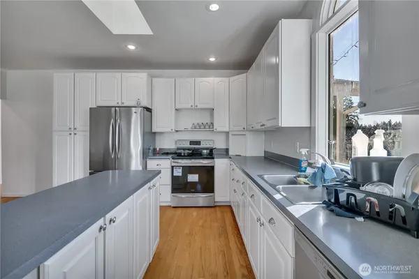 a kitchen with refrigerator a stove and a sink with wooden floor