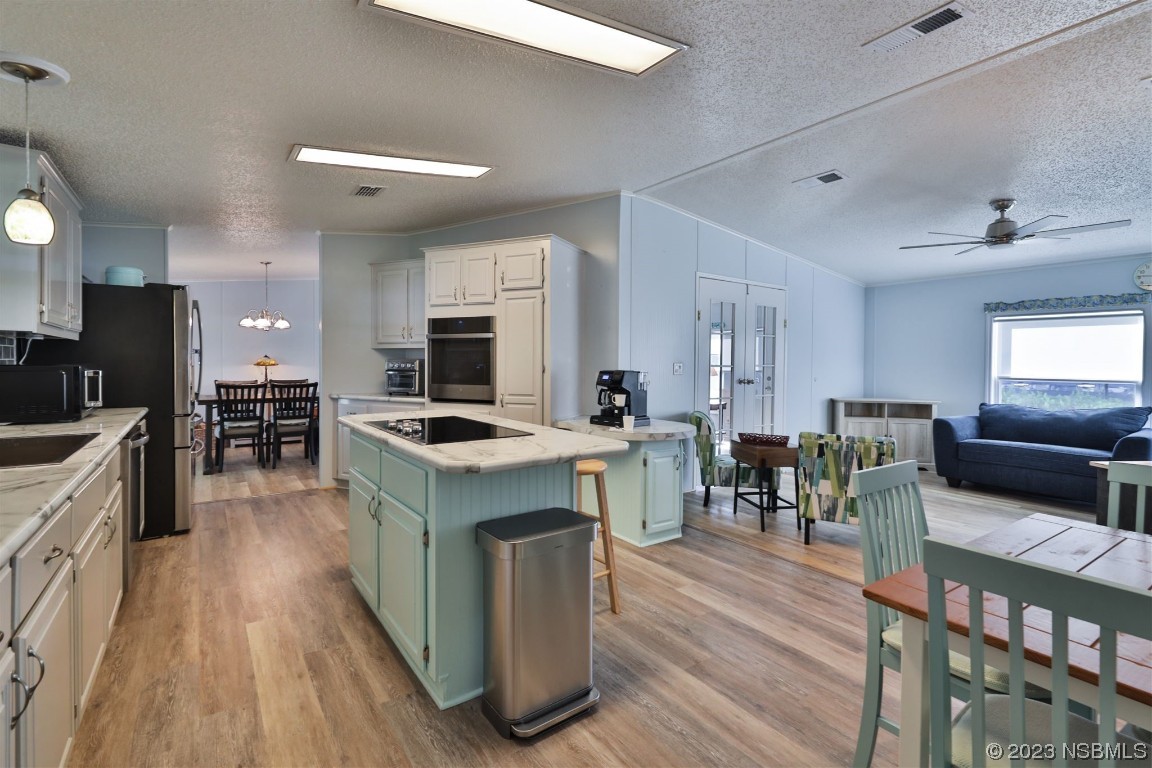 502 Topside Circle Edgewater, FL 32141 - Photo 11 of 28 a kitchen with stainless steel appliances granite countertop a stove top oven a sink dishwasher a dining table and chairs with wooden floor