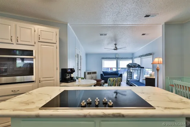 a view of kitchen with stainless steel appliances cabinets and flat screen tv
