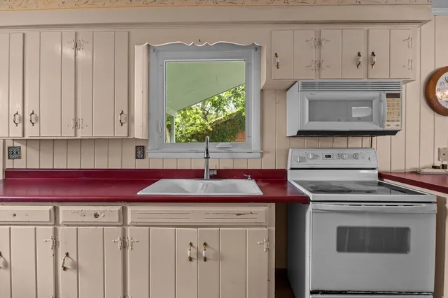 a kitchen with granite countertop white cabinets stainless steel appliances and a window