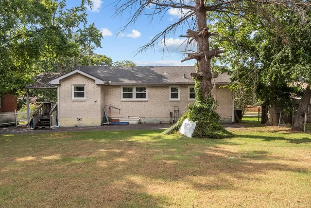 a view of a house with a yard and large tree