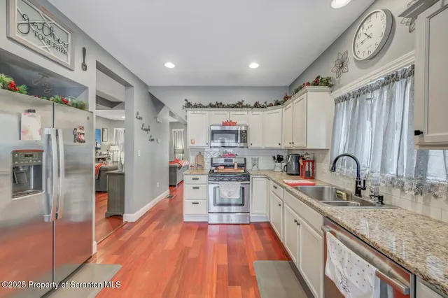 a large kitchen with stainless steel appliances granite countertop a lot of counter space and wooden floor