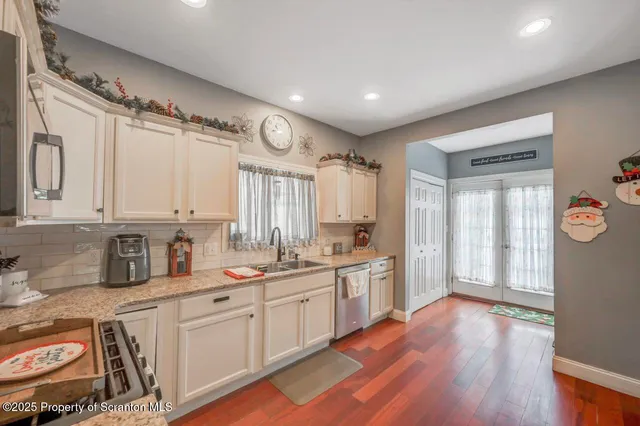 a kitchen with a sink cabinets wooden floor and stainless steel appliances