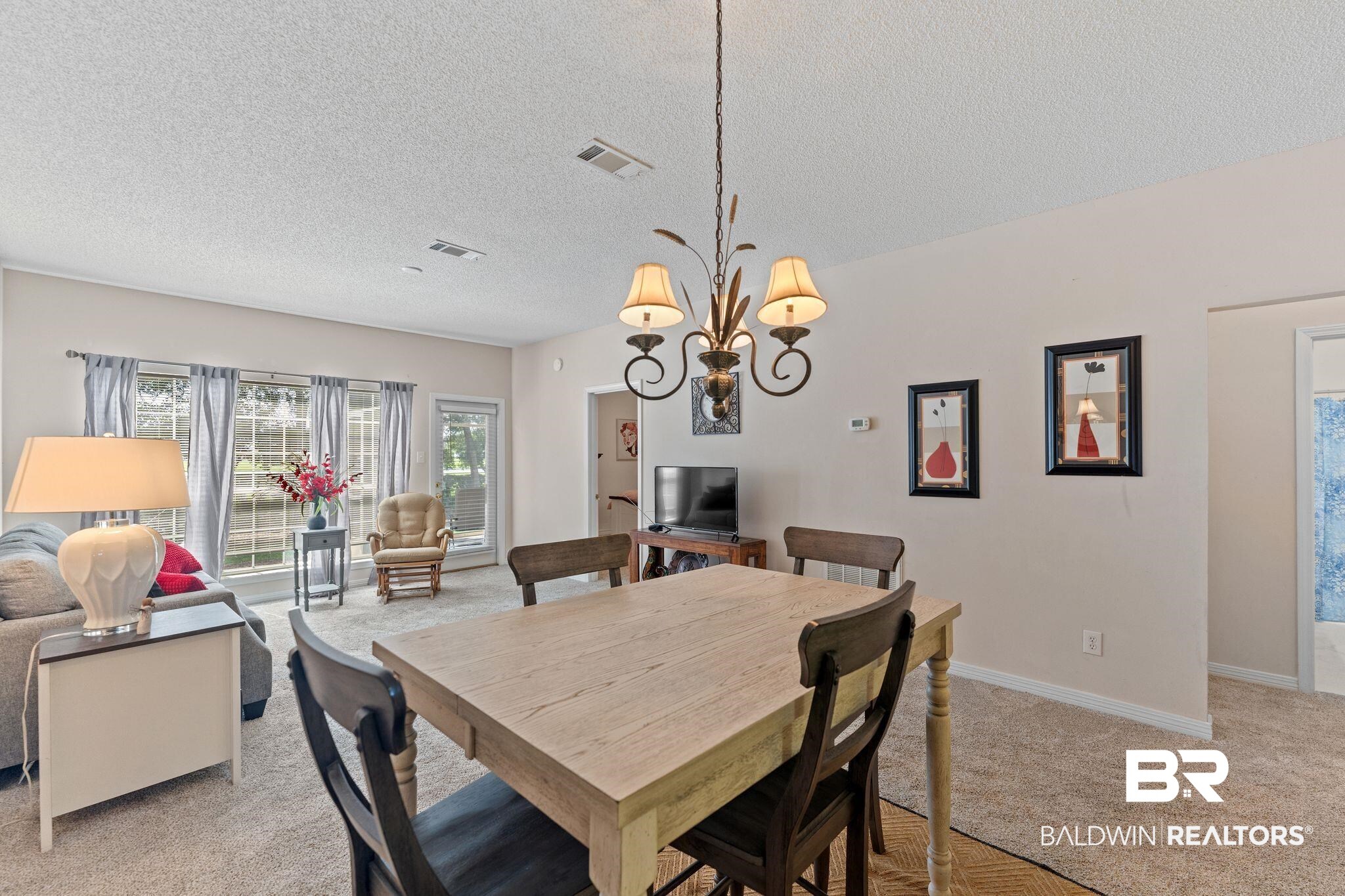 2651 South Juniper Street, Unit 203 Foley, AL 36535 - Photo 7 of 22 Dining area with light colored carpet, a chandelier, and a textured ceiling